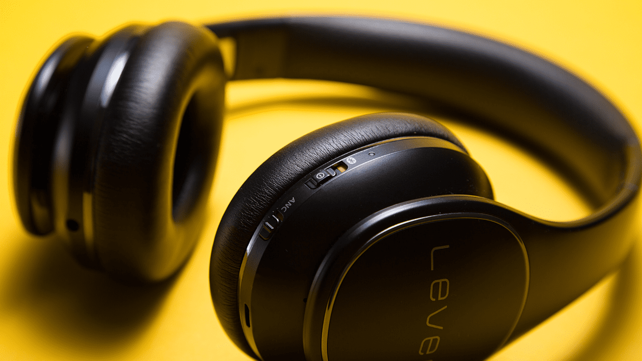 Stylish black wireless headphones placed against the yellow background